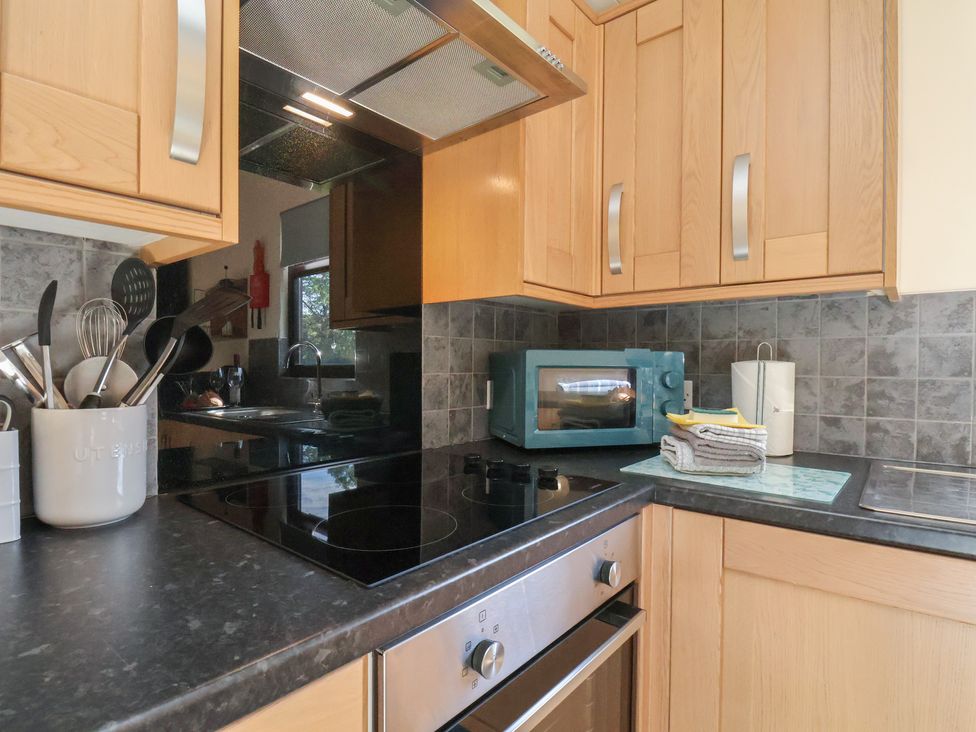 A kitchen with an induction cooktop and microwave at Foxglove Lodge in Saltburn-By-The-Sea