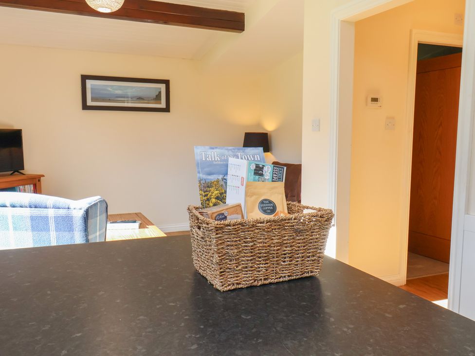 A living room with a basket of magazines on a table at Foxglove Lodge in Saltburn-By-The-Sea