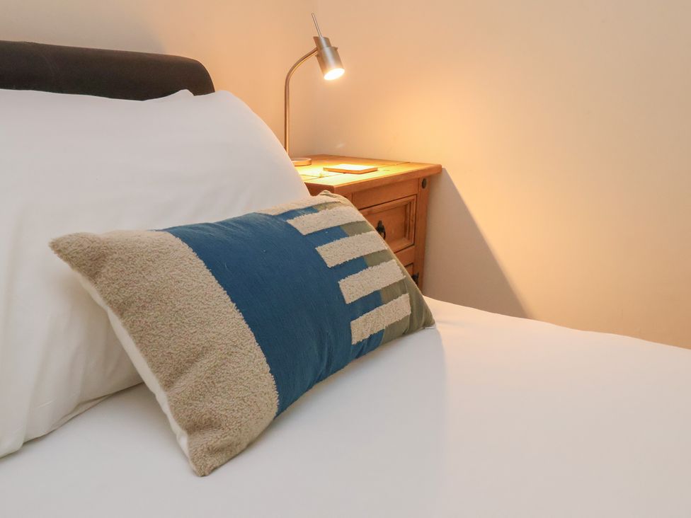 A bed with a pillow and a lamp on a bedside table at Foxglove Lodge, Saltburn-By-The-Sea