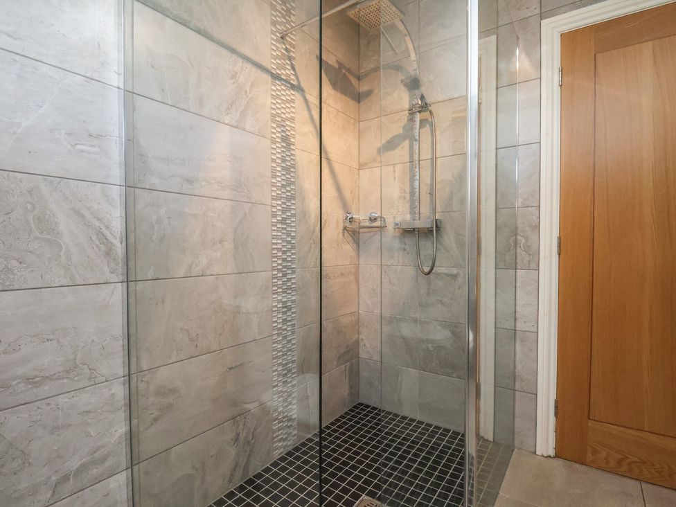 A shower with glass walls and a tiled floor at Foxglove Lodge in Saltburn-By-The-Sea