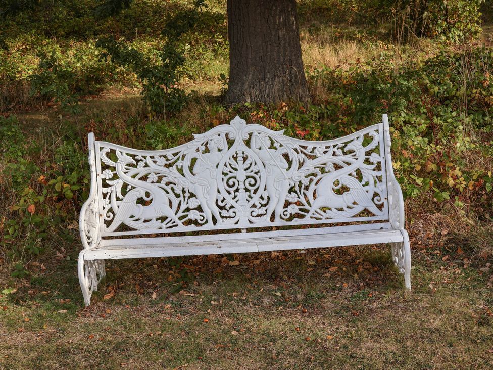 A white decorative bench near a tree in a garden at Foxglove Lodge Saltburn-By-The-Sea