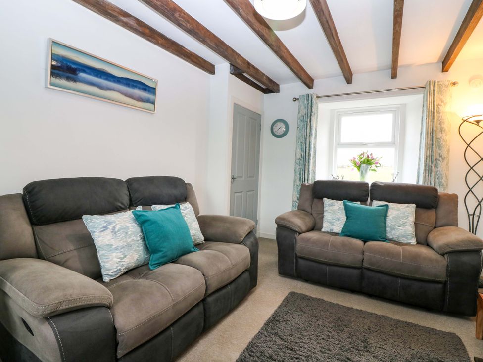 A living room with sofas, cushions, and a window at Birds Nest in Jedburgh