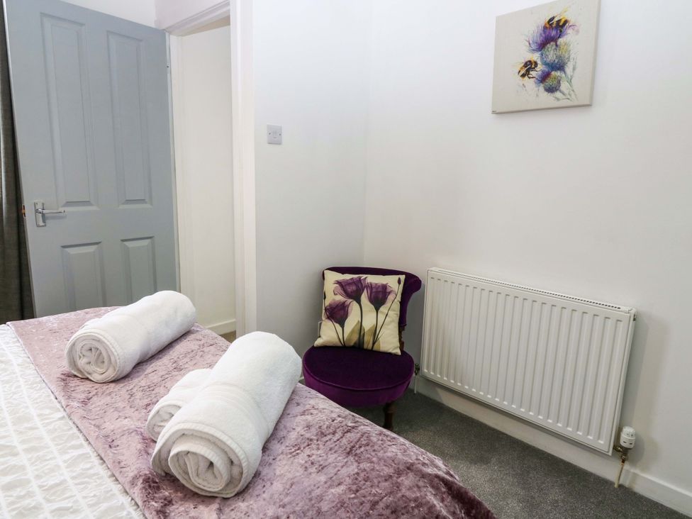 A bedroom with towels on the bed and a chair at Birds Nest in Jedburgh