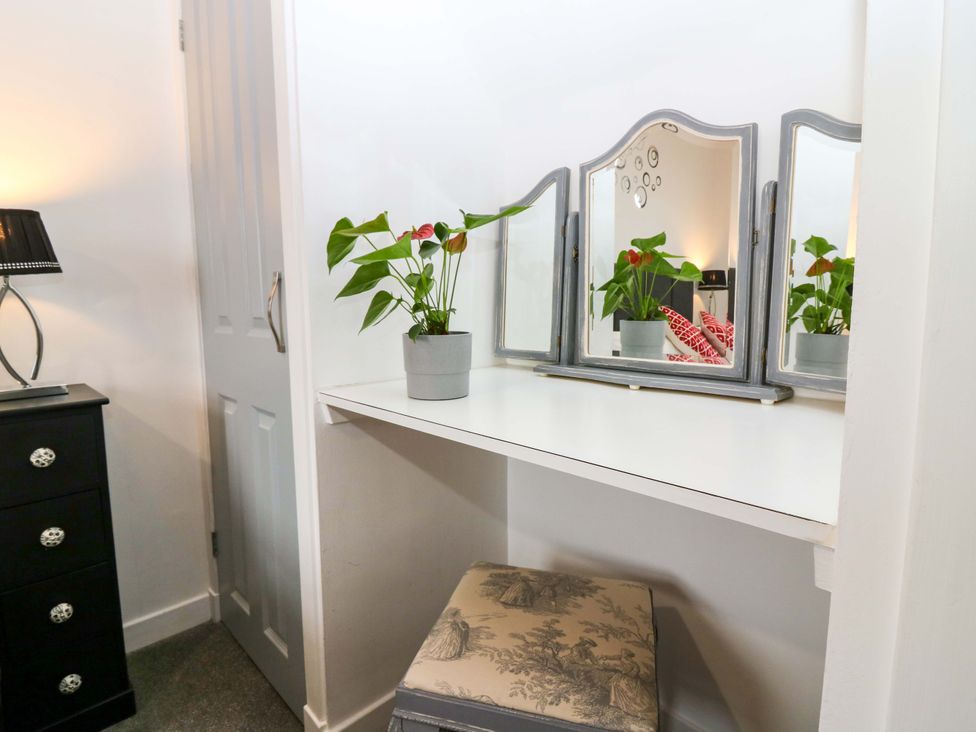 A bedroom area with a mirror and plant on the table at Birds Nest in Jedburgh