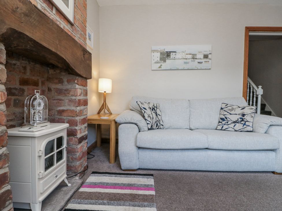 A living room with a sofa, lamp, and fireplace at Chapel Cottage in Filey