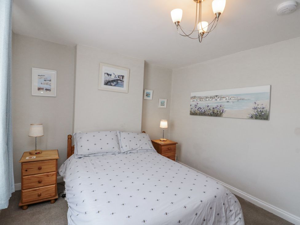 A bedroom with a bed, nightstands, and art on the wall at Chapel Cottage, Filey