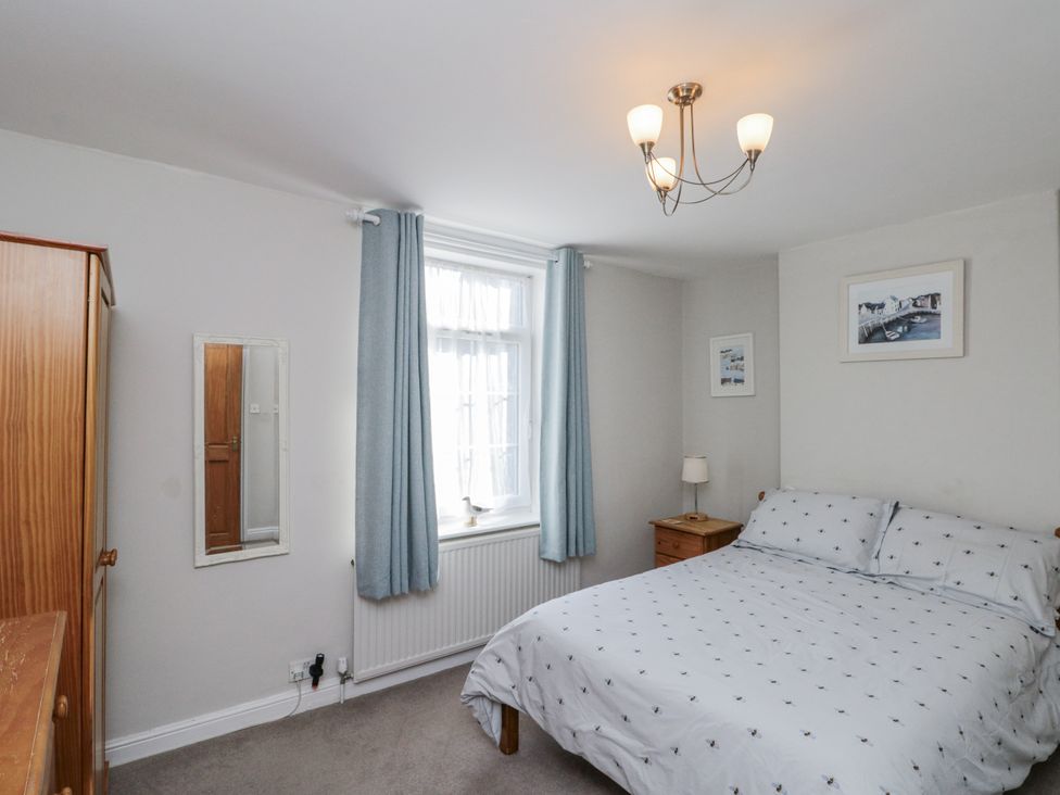 A bedroom with a bed and wardrobe at Chapel Cottage in Filey