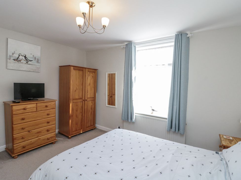 A bedroom with a bed and wooden furniture at Chapel Cottage in Filey
