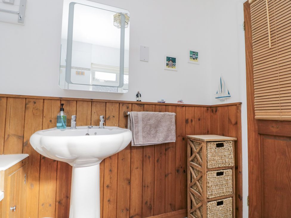 A bathroom with sink, mirror, towel and storage basket at Chapel Cottage in Filey