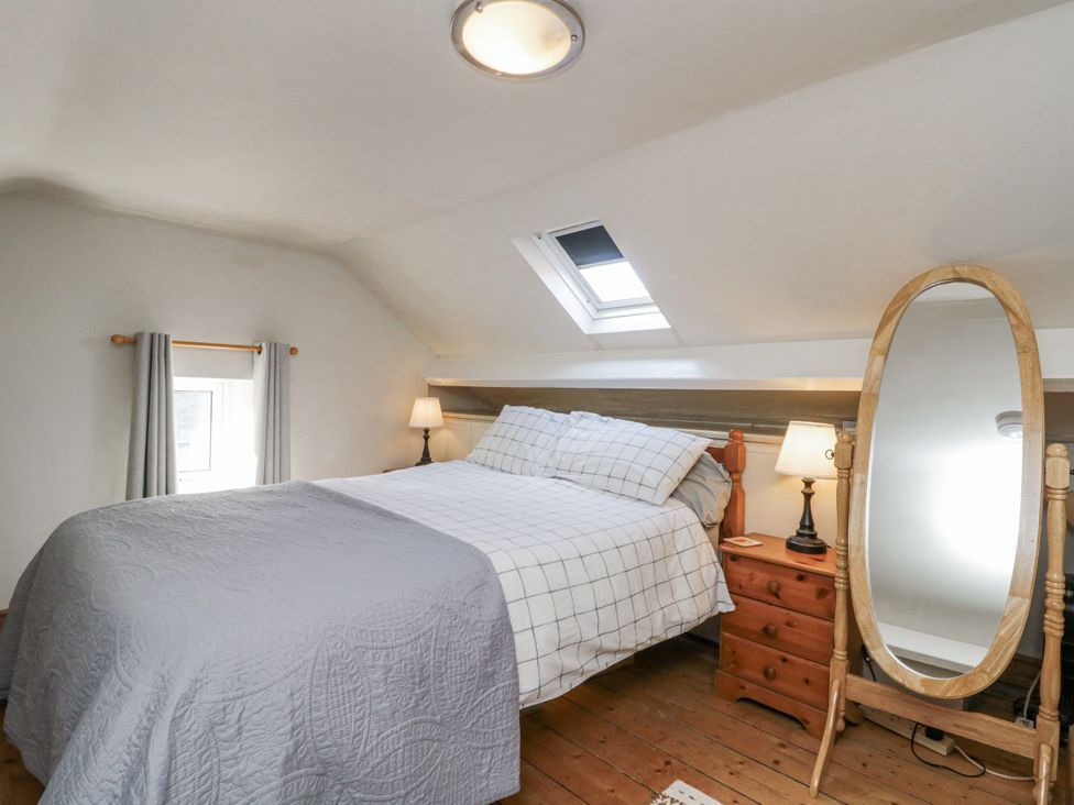 A bedroom with a bed and a mirror at Chapel Cottage in Filey