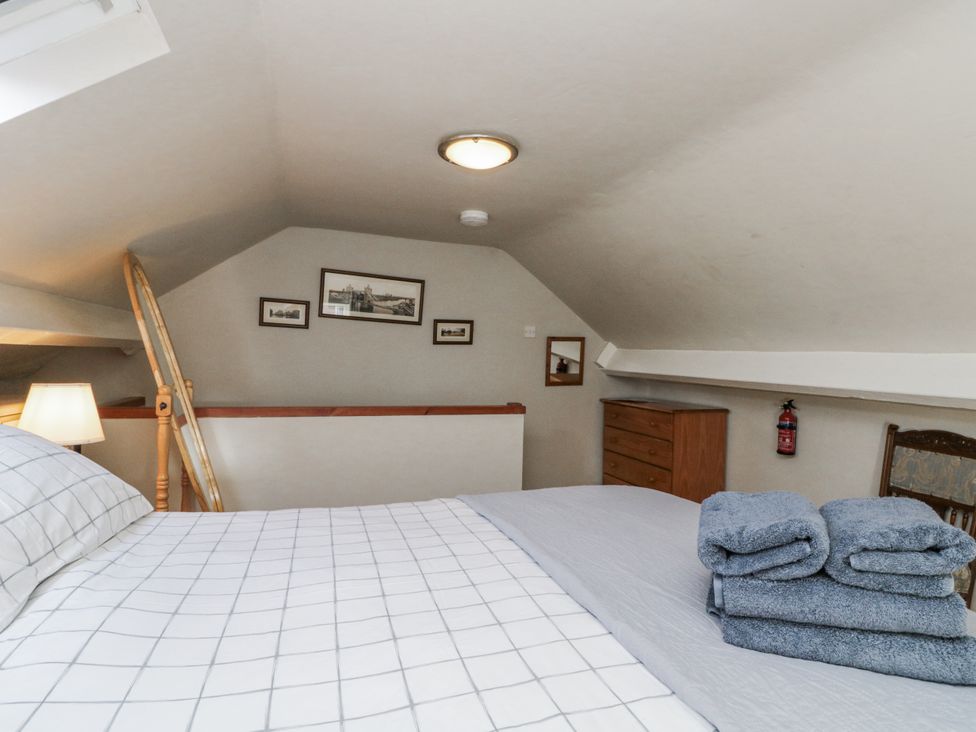 A bedroom with a bed and stairs at Chapel Cottage in Filey