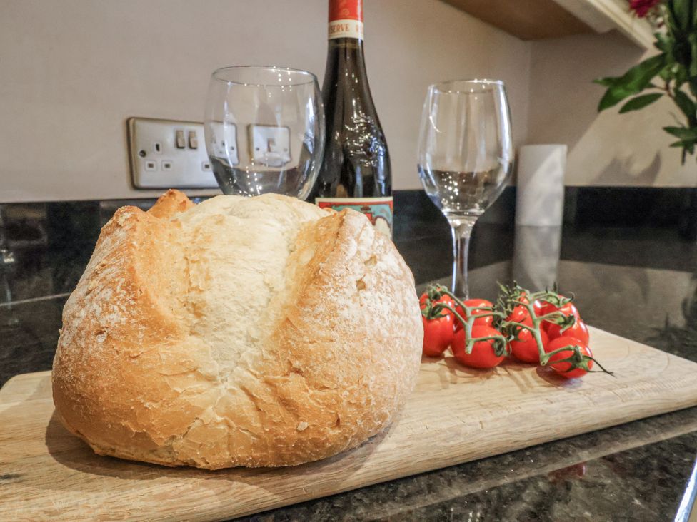 A kitchen with bread, wine glasses, tomatoes, and a wine bottle at The Manor House in Scarborough