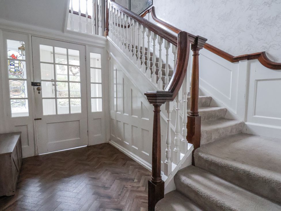 A hallway with a staircase and a bench at The Manor House in Scarborough