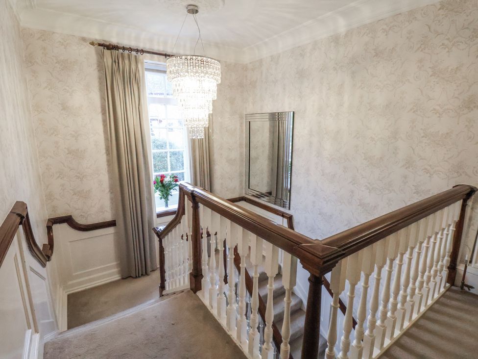 A staircase with a chandelier and mirror in the hallway at The Manor House in Scarborough