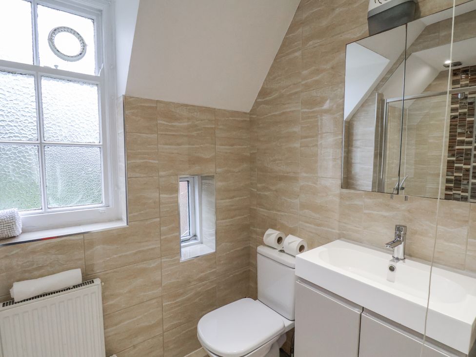 A bathroom with a sink, toilet, and mirror at The Manor House in Scarborough