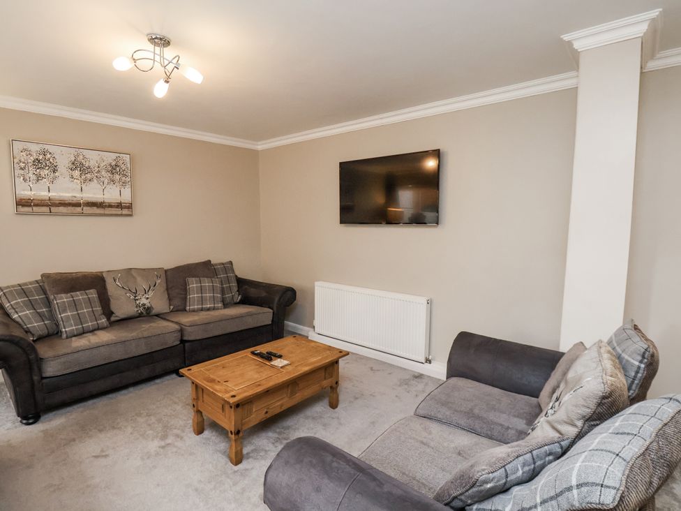 A living room with a sofa, coffee table, and television at Tennyson House in Scarborough