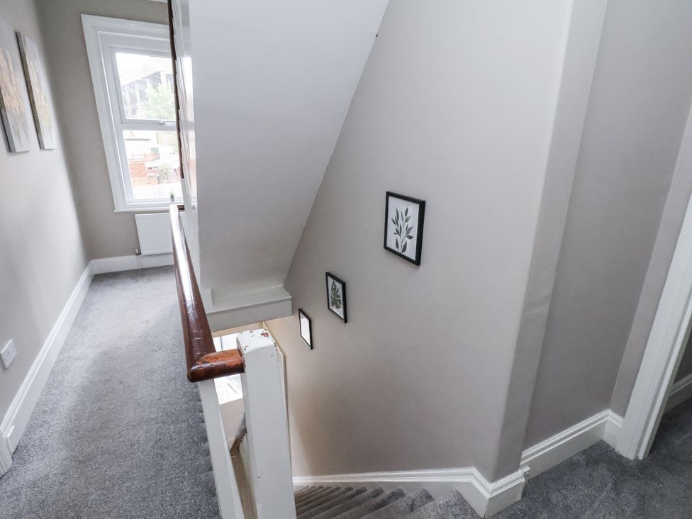 A staircase in a hallway with framed pictures at Tennyson House Scarborough