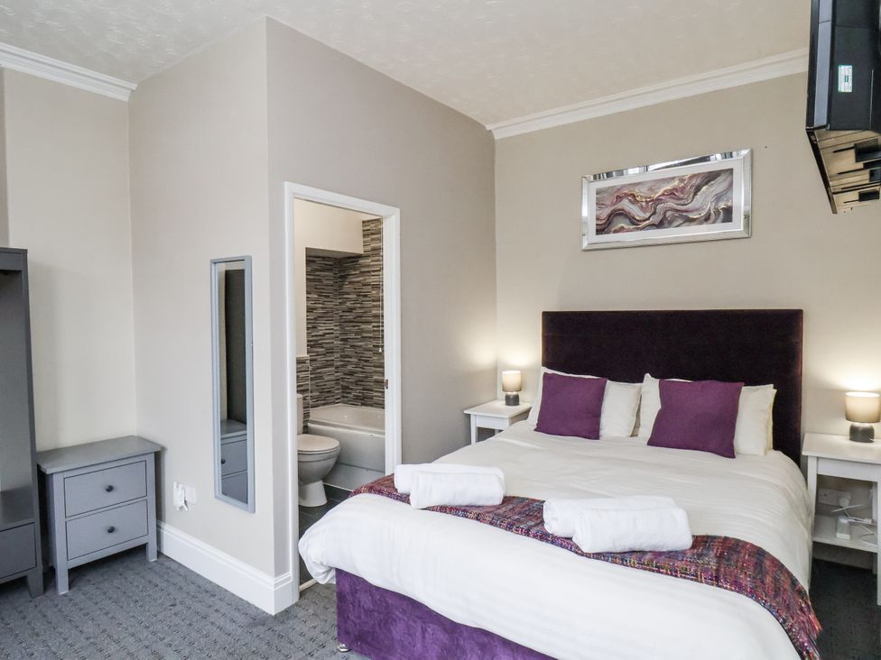A bedroom with a bed and a bathroom door at Tennyson House in Scarborough