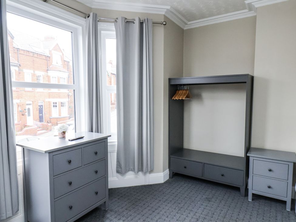 A bedroom with a dresser and a clothes rack at Tennyson House in Scarborough