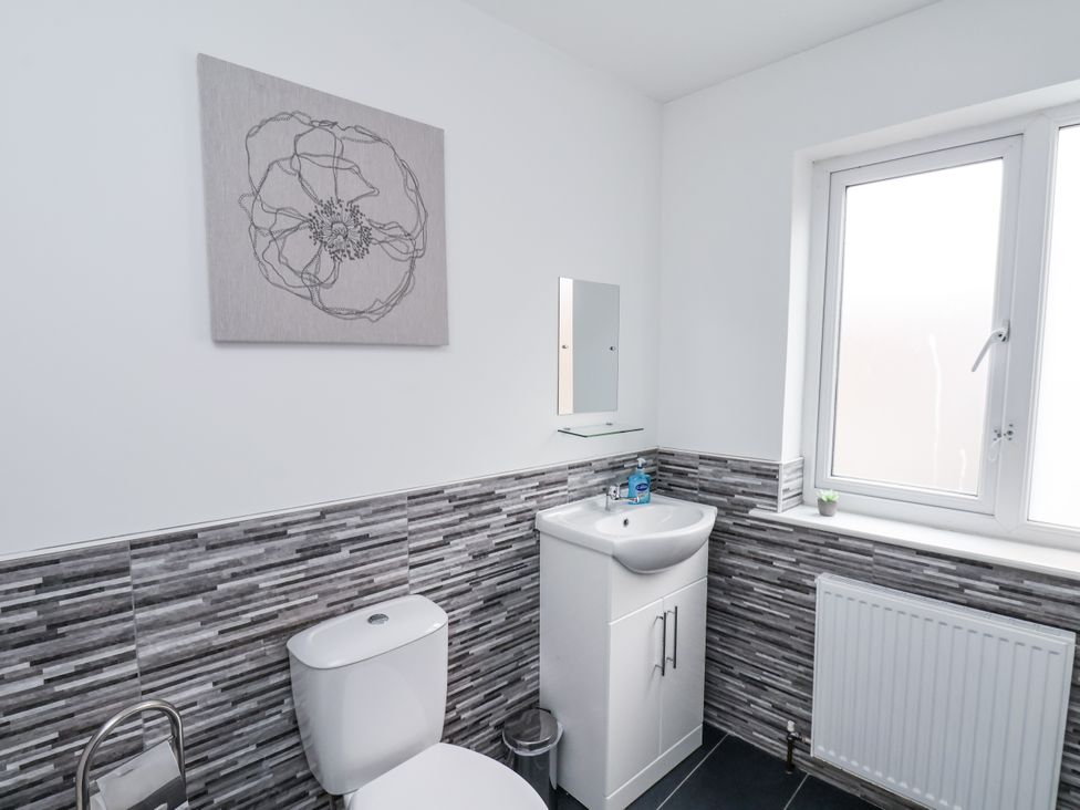 A bathroom with a toilet, sink, and window at Tennyson House in Scarborough