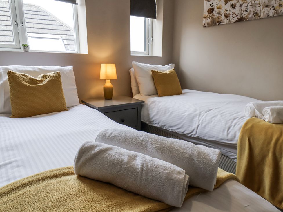 A bedroom with two beds and a bedside lamp at Tennyson House in Scarborough
