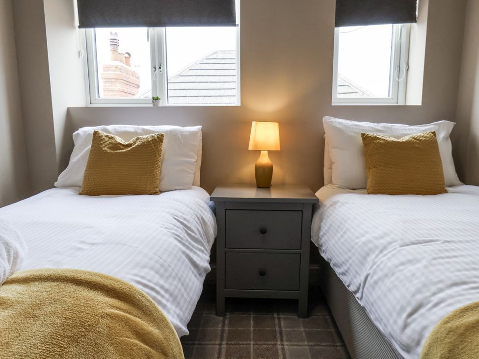 A bedroom with two beds and a lamp on a nightstand at Tennyson House in Scarborough
