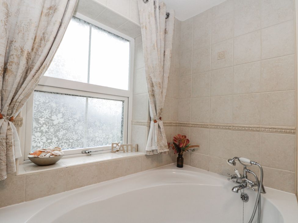 A bathroom with a bathtub and a window at Dove Cottage in Sleights