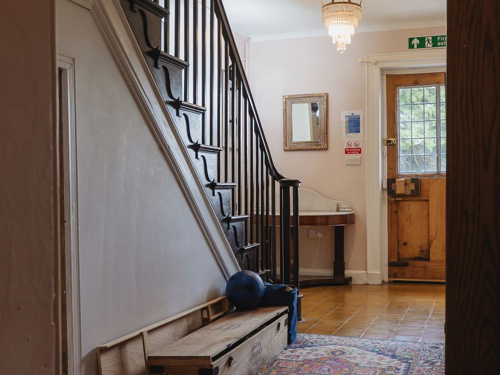 A hallway with a staircase and a door at Cwmalis Hall in Llangollen