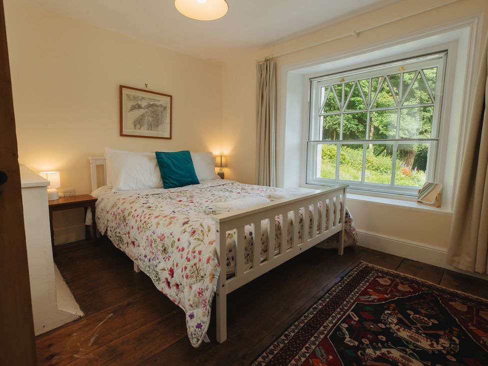 A bedroom with a bed and a window overlooking greenery at Cwmalis Hall Llangollen