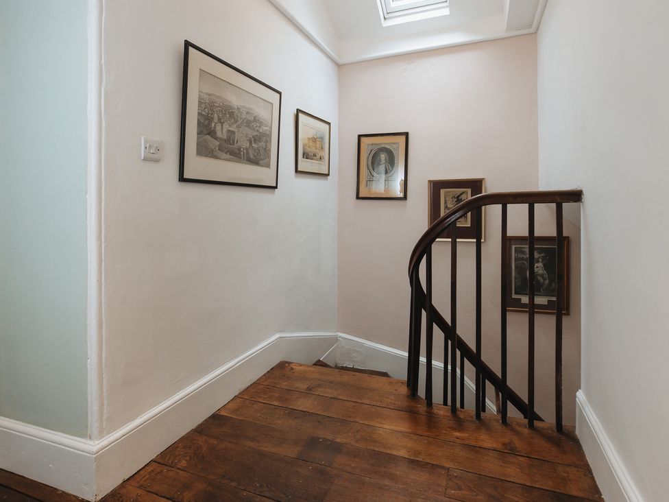A staircase with framed artwork on walls at Cwmalis Hall in Llangollen