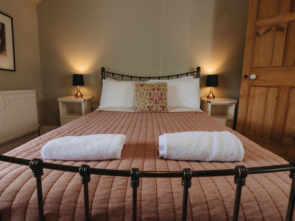A bedroom with a bed and nightstands at Cwmalis Hall Llangollen