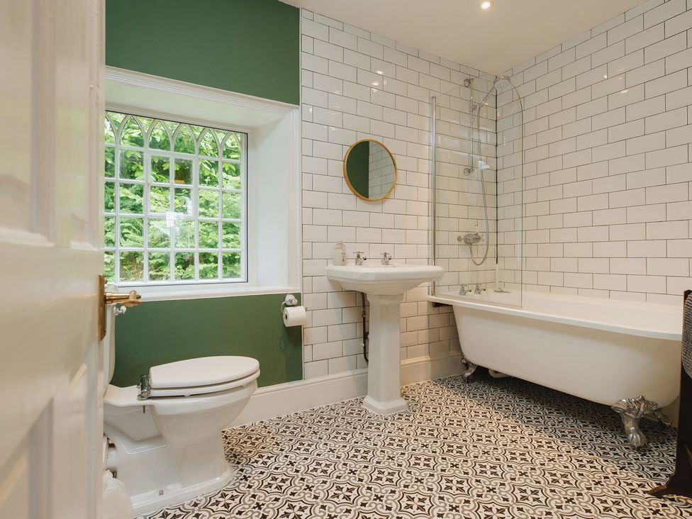 A bathroom with a bathtub, sink, and toilet at Cwmalis Hall in Llangollen