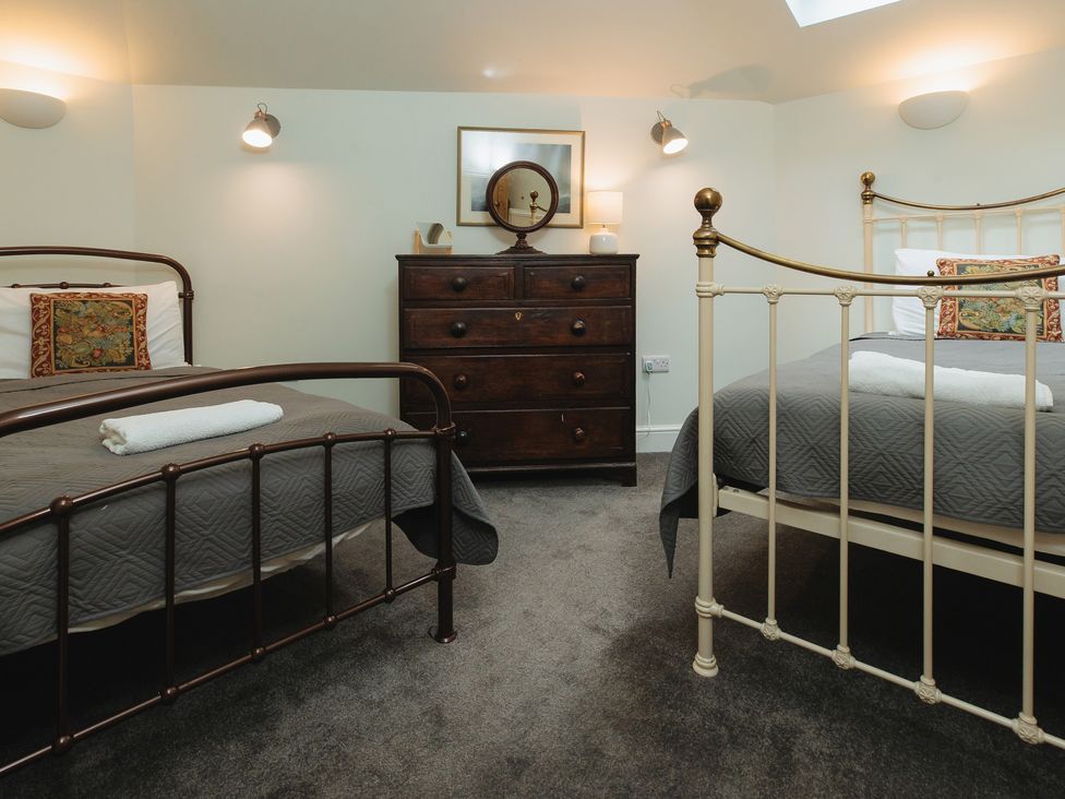A bedroom with two beds and a dresser at Cwmalis Hall Llangollen