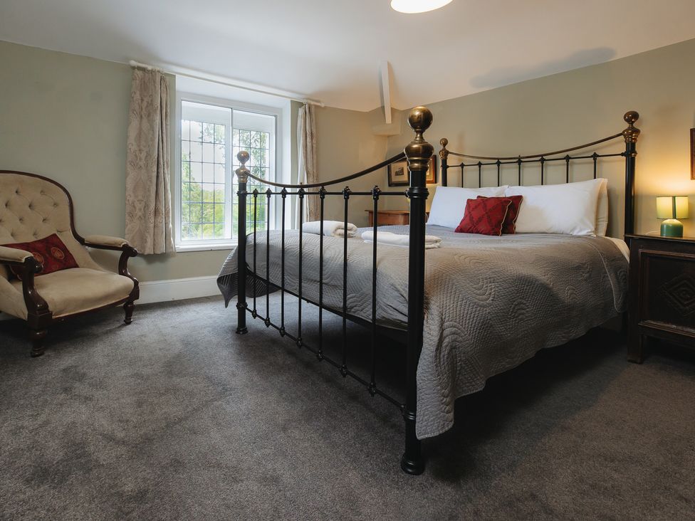 A bedroom with a bed and armchair at Cwmalis Hall Llangollen