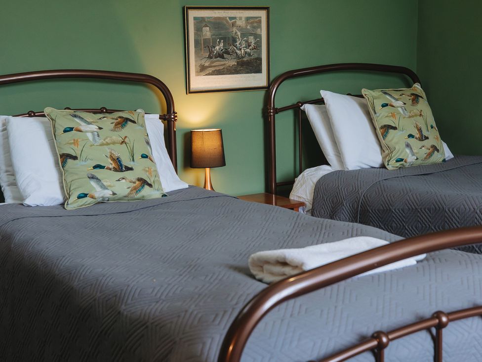 A bedroom with two beds and a painting at Cwmalis Hall Llangollen