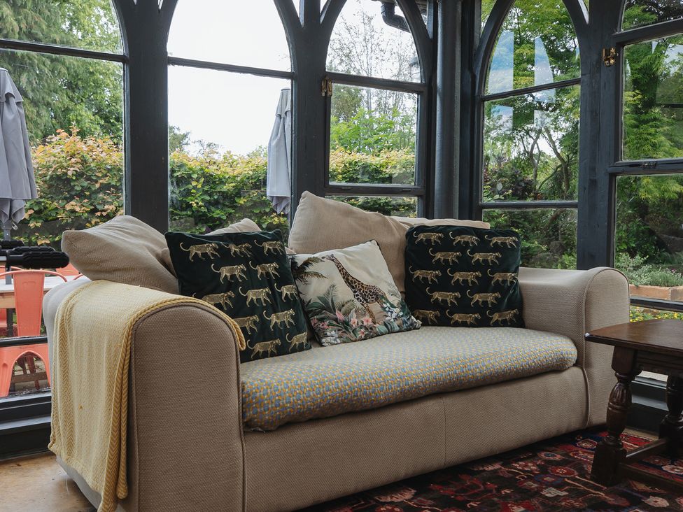 A snug with a sofa and cushions at Cwmalis Hall Llangollen