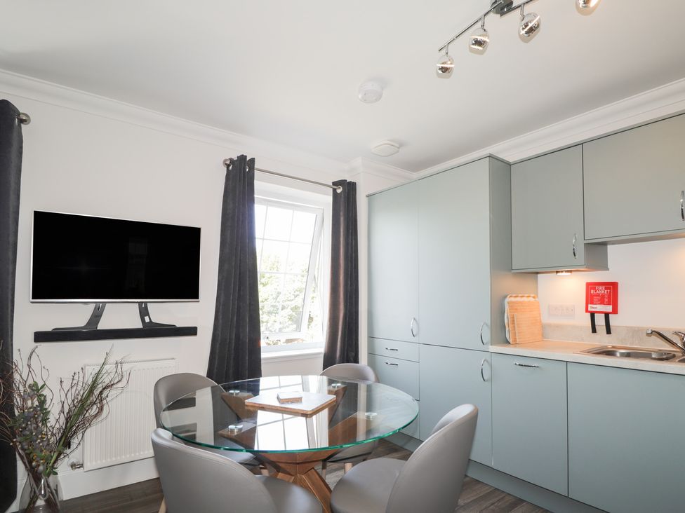A kitchen with cabinets and a table at The Nook in Culloden