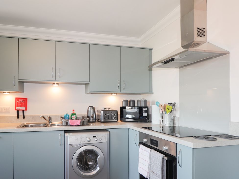 A kitchen with cabinets, appliances and a washing machine at The Nook in Culloden