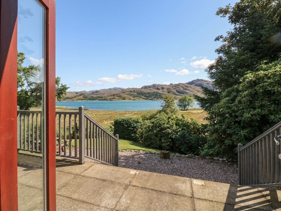 A view from a deck overlooking a lake and mountains at Clearwater House Roshven near Glenuig
