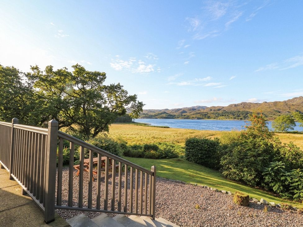 A view of a lake and trees from a deck at Clearwater House in Roshven near Glenuig