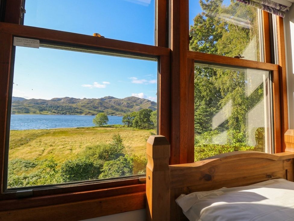 A view from a bedroom window showing mountains and water at Clearwater House in Roshven near Glenuig
