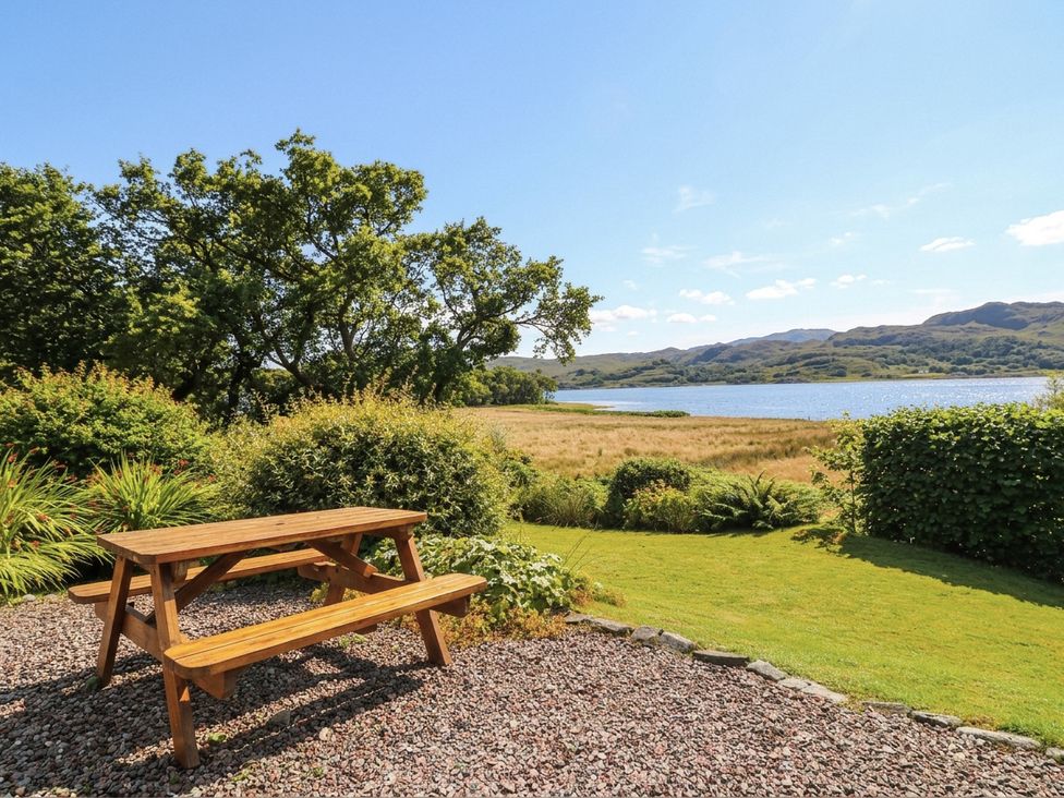 A garden with a picnic table overlooking a lake at Clearwater House in Roshven near Glenuig