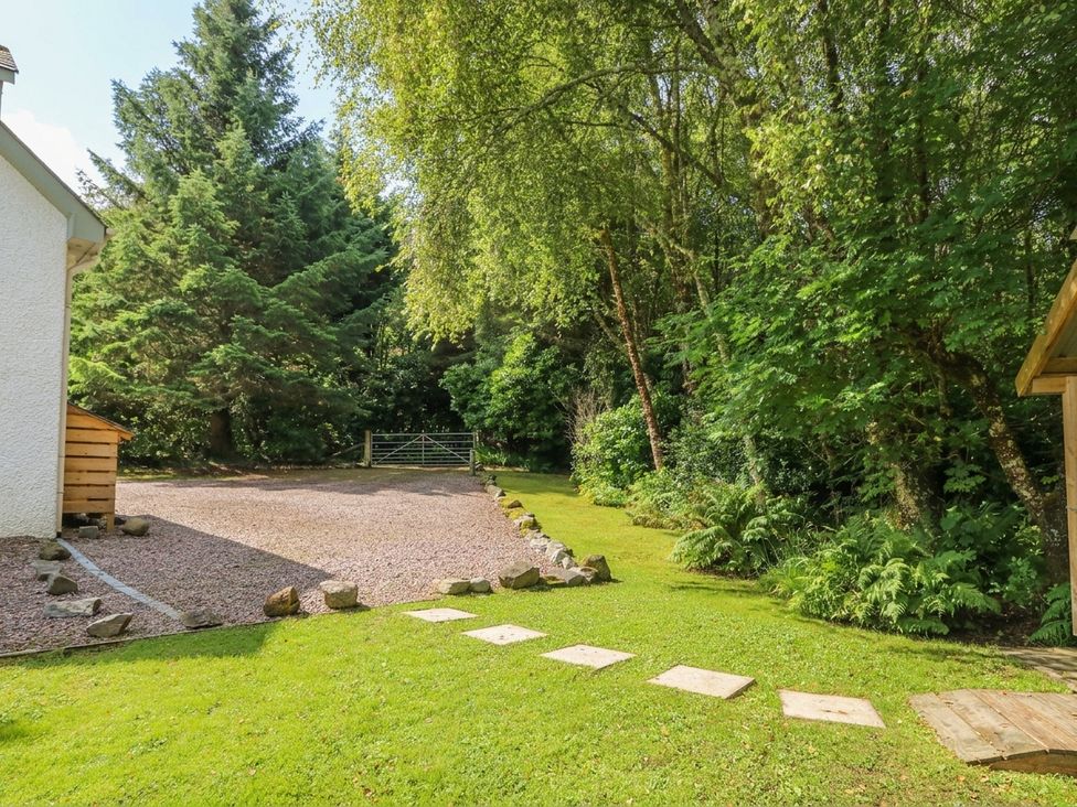 A garden with gravel path and trees at Clearwater House in Roshven near Glenuig