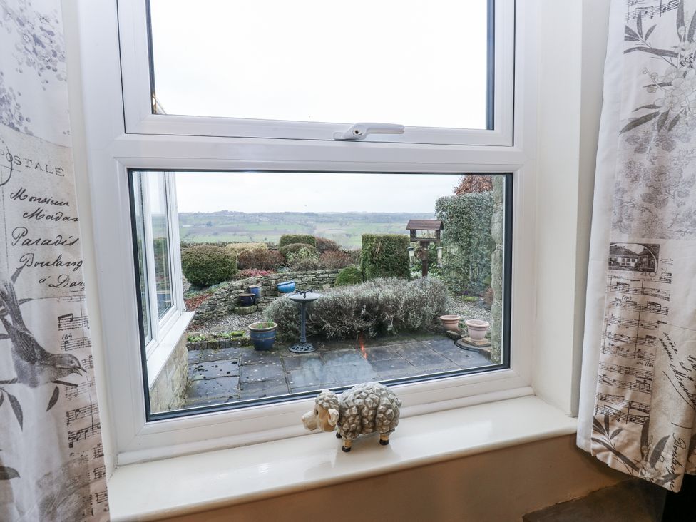 A window view showing a garden and a sheep figurine at Kelda Garthr (Tranquil Garden) Middleham