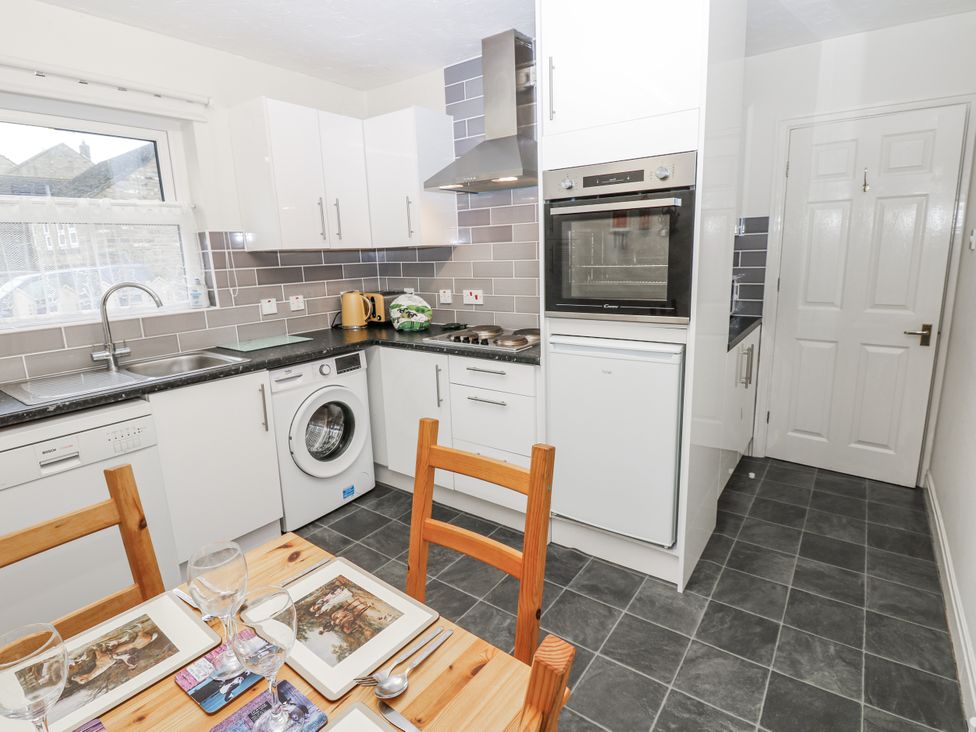 A kitchen with appliances and dining table at Kelda Garthr (Tranquil Garden) Middleham