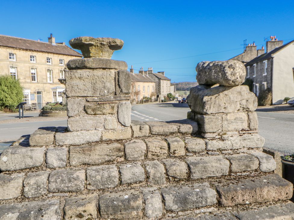 A stone structure with a road and buildings in the background at Kelda Garthr (Tranquil Garden) Middleham