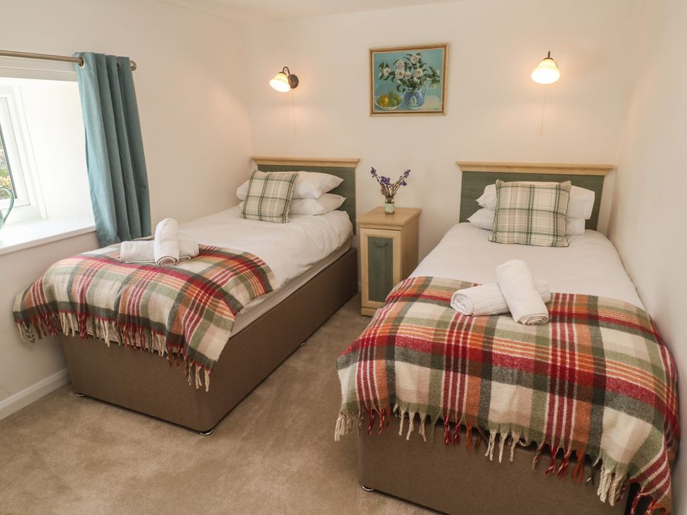 A bedroom with twin beds and a bedside table at Meadowside in Mousehole