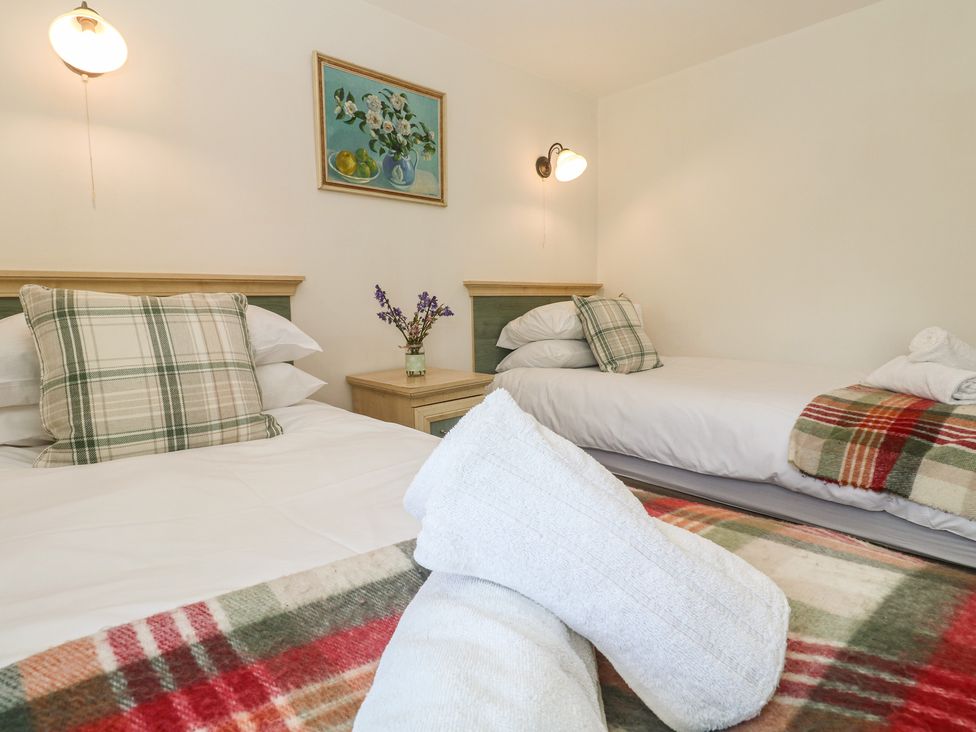 A bedroom with two beds and a floral vase at Meadowside in Mousehole