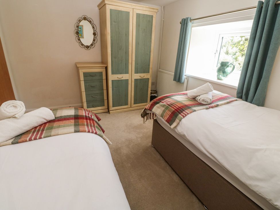 A bedroom with two beds and a wardrobe at Meadowside in Mousehole