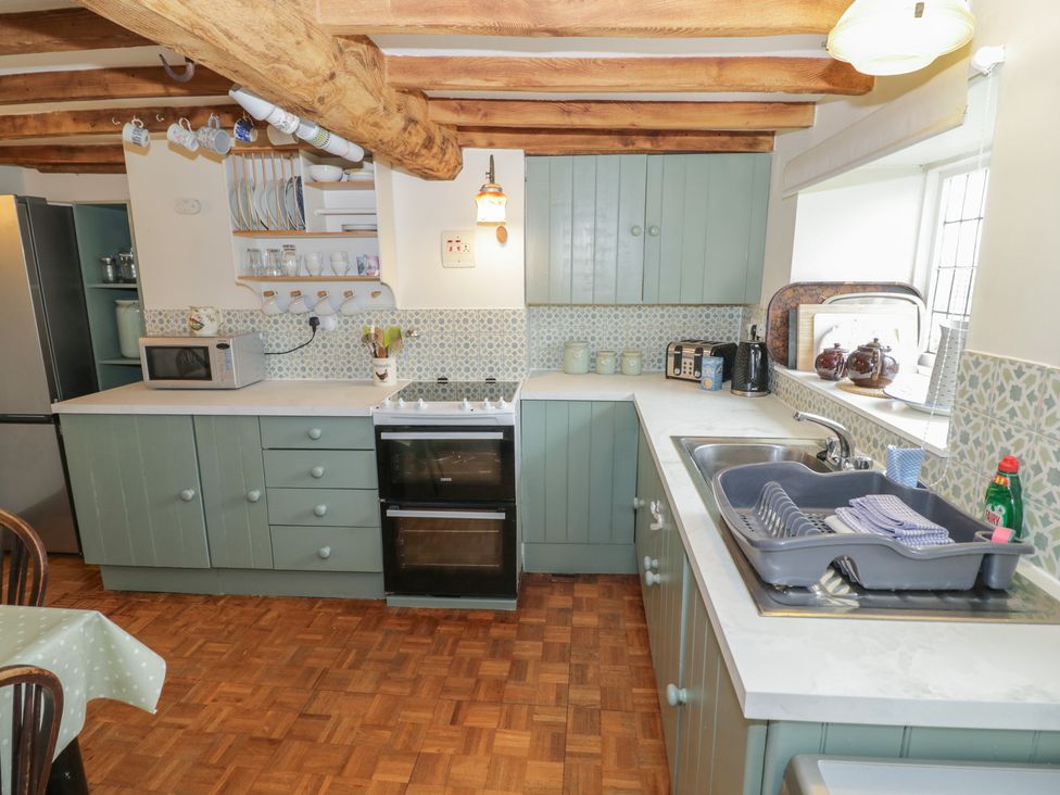 A kitchen with cabinets, stove, sink, and microwave at Priors Mead Claydon near Cropredy